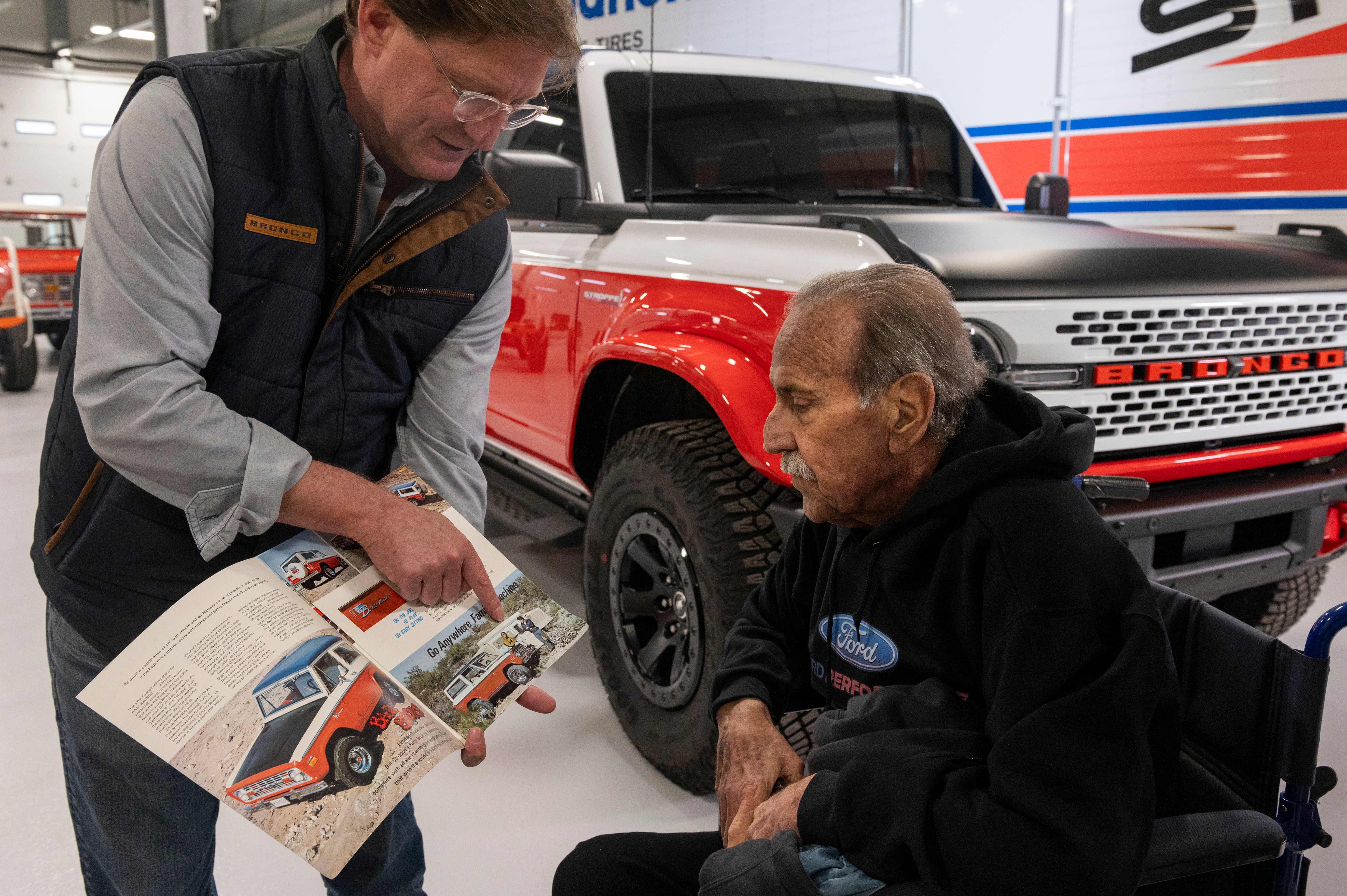 From left, Ted Ryan, archives and heritage brand manager at Ford Motor Co., shows Willie Stroppe historical items and photos while standing next to the new Ford Stroppe Bronco, on Tuesday, Feb. 6, 2024 in Johnstown, Colorado. Rachel Woolf for Ford